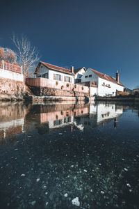 Buildings by river against sky in city