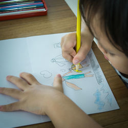 Low section of boy holding paper with text on table