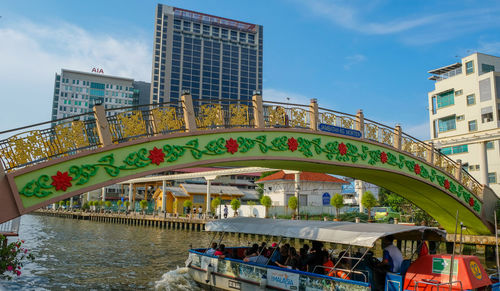 People on footbridge over river in city