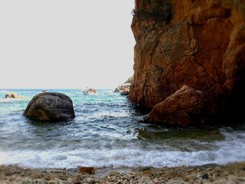 Rock formation in sea against clear sky