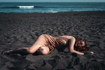 Woman lying on sand at beach