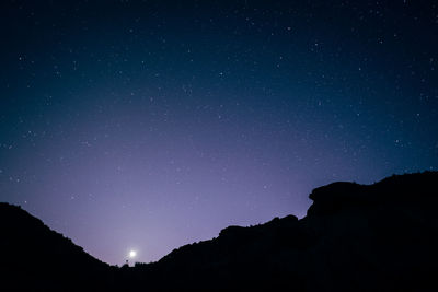 Low angle view of silhouette mountain against star field at night