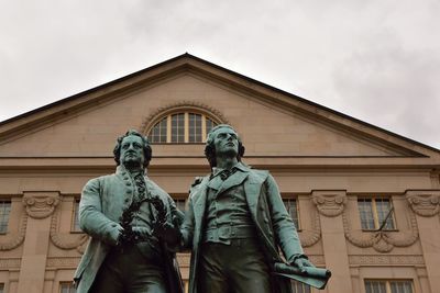 Low angle view of statue against building against sky