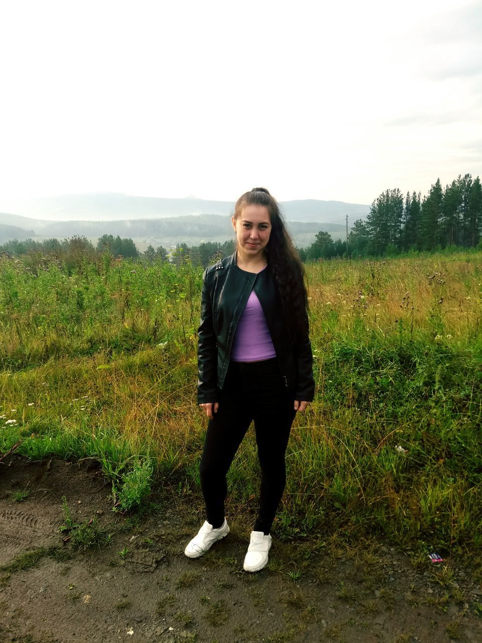 one person, plant, portrait, standing, full length, looking at camera, young adult, front view, leisure activity, sky, lifestyles, real people, field, land, grass, nature, casual clothing, green color, landscape, outdoors