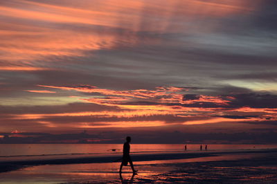 Silhouette person on beach against sky during sunset