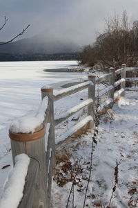 Snow covered railing by snowcapped mountain against sky