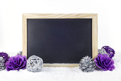 Close-up of blackboard with christmas decorations on snow