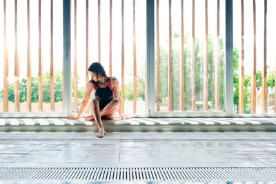 Full length of woman sitting by window