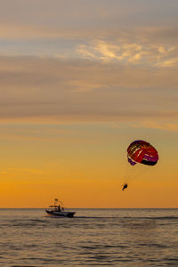 Silhouette people on sea against sky during sunset