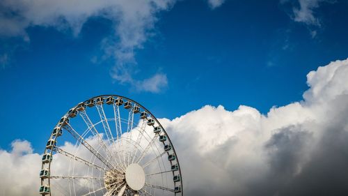 Cropped image of ferris wheel against cloudy sky