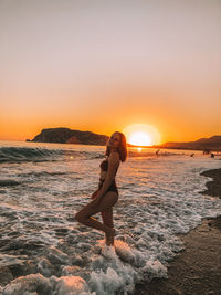 Full length of woman on beach against sky during sunset