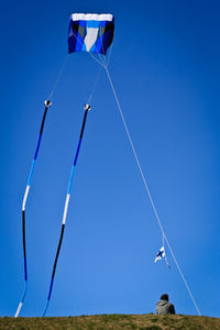 Low angle view of flags against clear blue sky