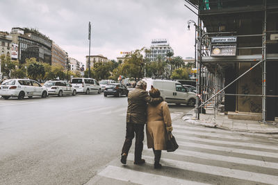 Rear view of people walking on street in city