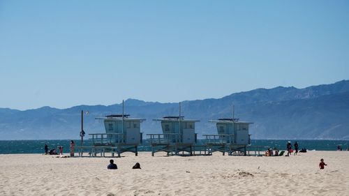 Lifeguard huts on sand at beach against clear blue sky