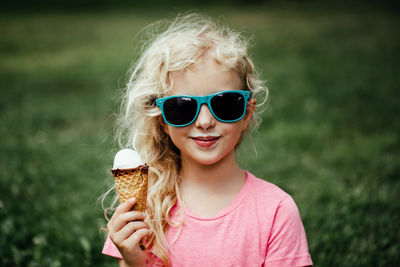 Cute funny girl in sunglasses with dirty nose and moustaches eating ice cream from waffle cone