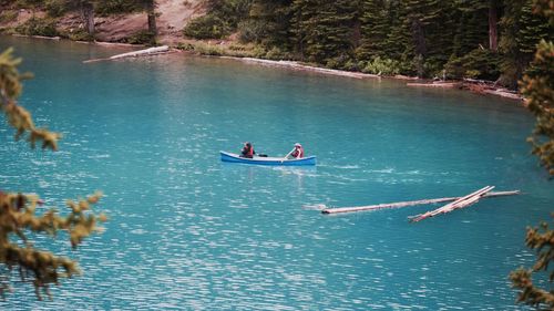 High angle view of people oaring boat in blue lake