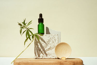 Cbd oil in bottle and a cannabis bush, hemp in still life on geometric podium