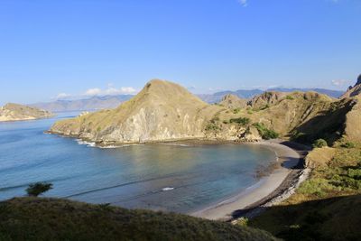 Scenic view of sea and mountains against clear blue sky
