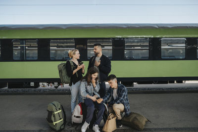 Family with luggage talking to each other while waiting in front of train at railroad station