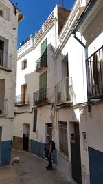Rear view of woman walking on alley amidst buildings in city