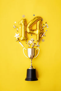 Directly above shot of trophy against yellow background