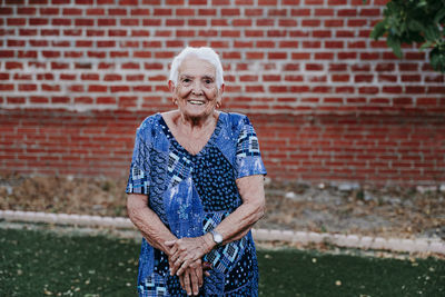 Portrait of smiling young woman standing against brick wall