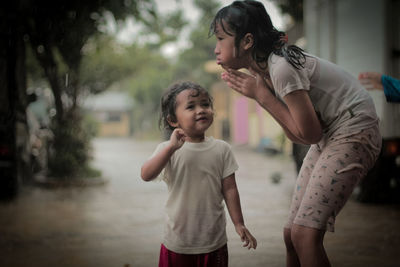 Wet siblings shivering while standing outdoors during rainy season