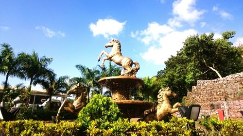 Statue by trees against sky