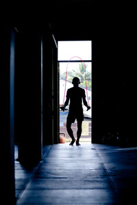 Silhouette man skipping by door of darkroom