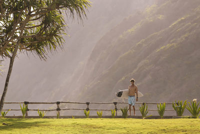 Young man walking and carrying surfboard