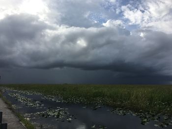 Scenic view of field against storm clouds