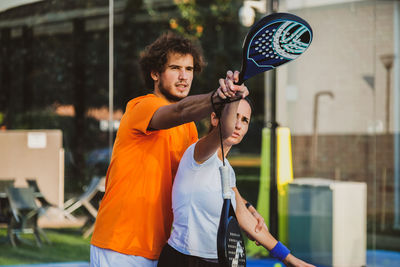 Male tennis player teaching tennis to woman