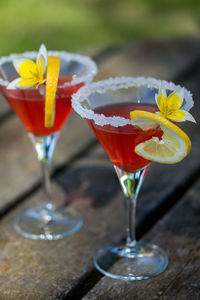 High angle view of drink garnished with yellow flower with lemon slice on wooden table