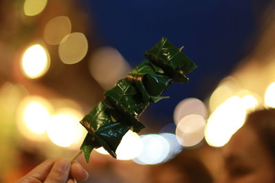 Close-up of hand holding illuminated candles