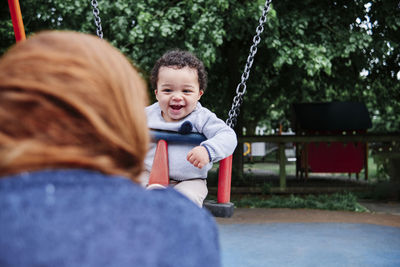 Smiling boy swinging in playground at park