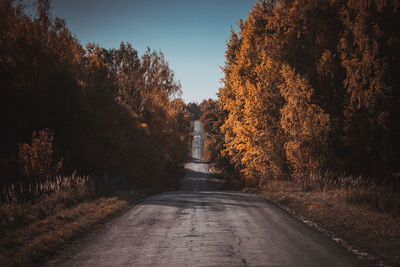 Road amidst trees against sky during autumn