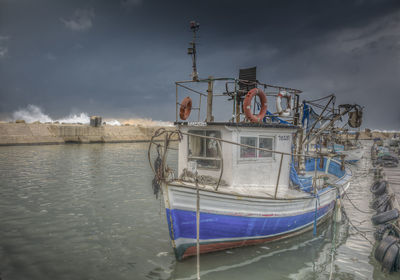 Fishing boat moored in sea against sky