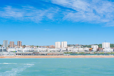 Scenic view of sea by buildings against blue sky