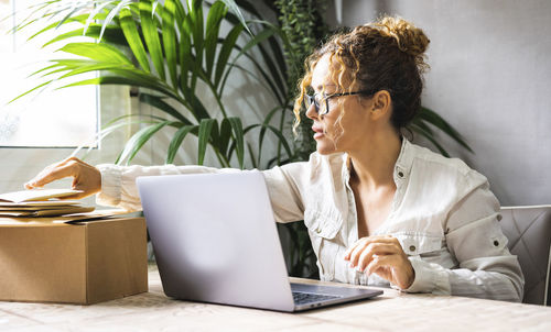 Businesswoman using laptop while sitting on table