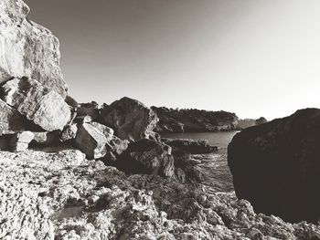 Rock formations on shore against clear sky