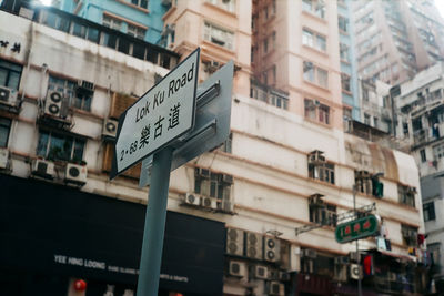 Low angle view of road sign against buildings in city