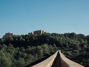 Panoramic view of trees and buildings against clear blue sky