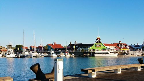 Boats moored on river by buildings against clear sky