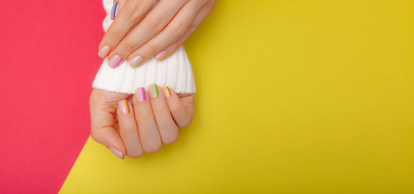 Close-up of woman hand on yellow background