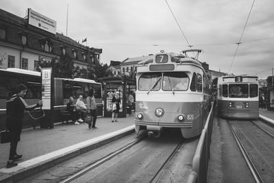 People on railroad tracks in city against sky