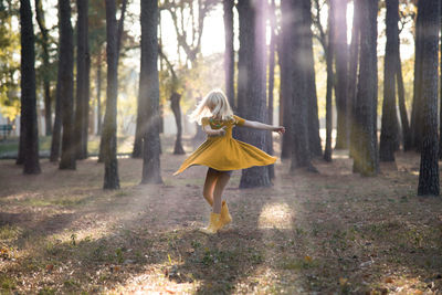 Girl dancing against trees in forest