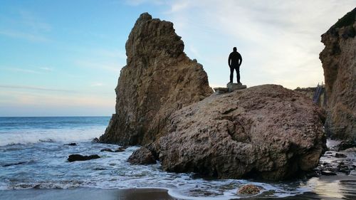 Man standing on cliff by sea