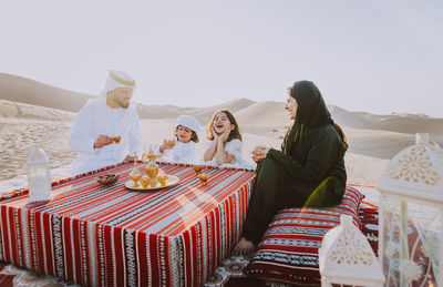 Group of people sitting on table against sky