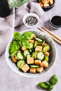 Vegetarian salad with fried tofu and fresh cucumbers in a bowl on the table vertical view