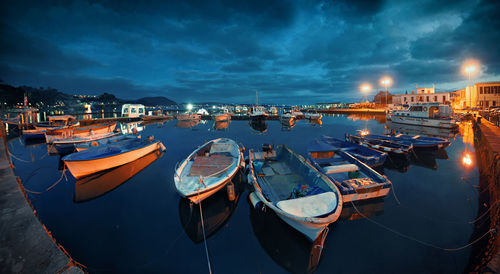 Boats moored in illuminated city at night